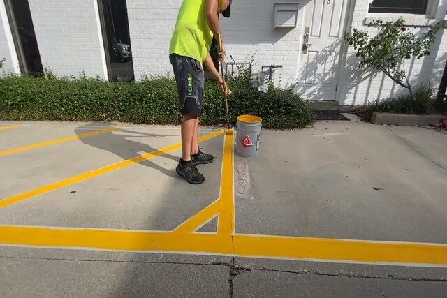 Asphalt Paving worker doing manual striping on parking lot